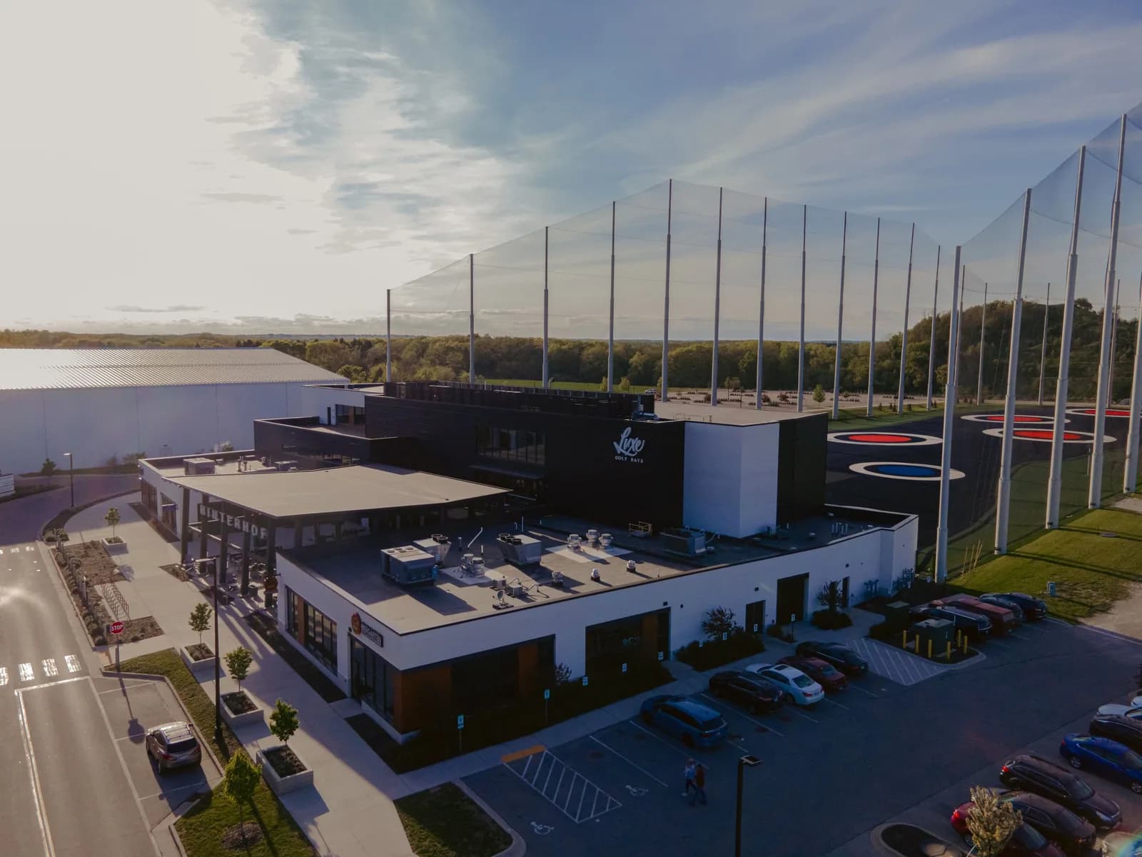 Aerial view of Luxe Golf Bays building with netted practice area and colorful circular targets