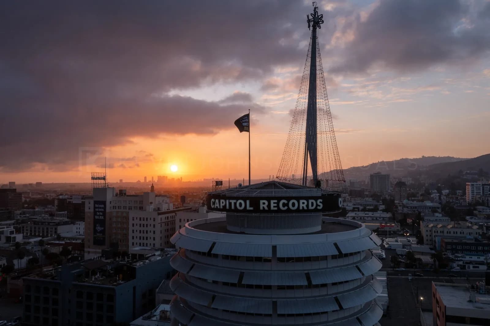 Capitol Records circular building at sunset with a city skyline and a tall lattice tower