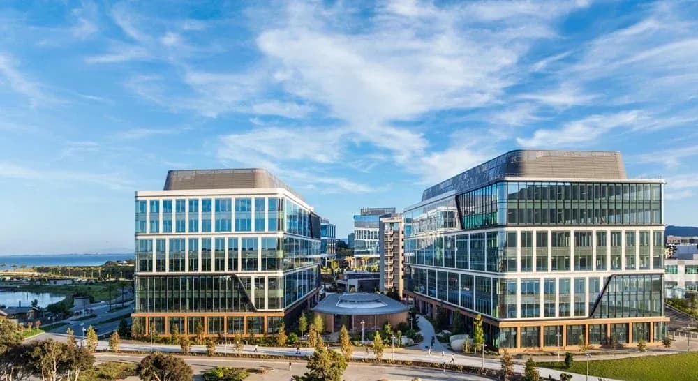 Two modern glass office buildings facing each other with a central courtyard and blue sky