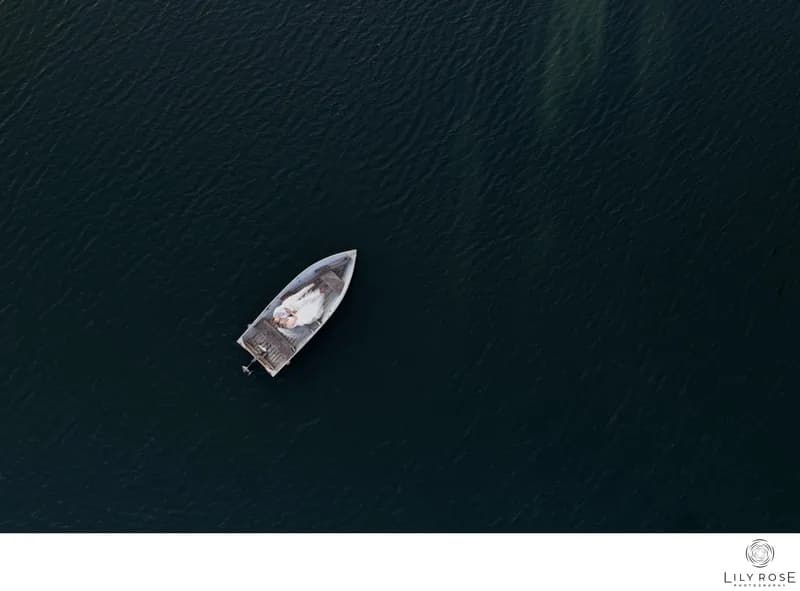 Small boat on dark blue water, aerial view; logo watermark bottom right