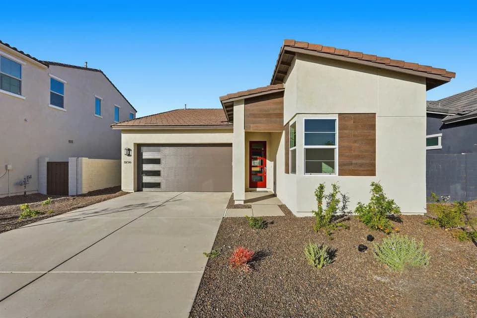 Single-story modern house with red front door, two-car garage, driveway and gravel landscaping