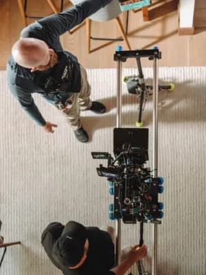 Overhead view of two people working on a drone mounted on a metal frame in a workshop