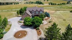 Aerial view of a two-story brick house with a circular driveway and surrounding trees