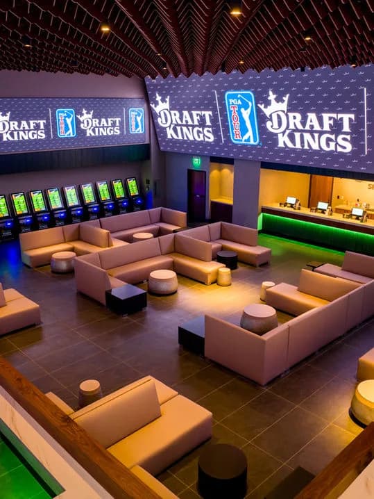 Elevated view of a modern lounge with modular seating, gaming kiosks and large DraftKings signage
