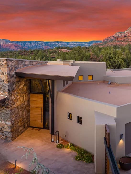 Modern southwestern house entry and rooftop with desert landscape and orange sunset sky