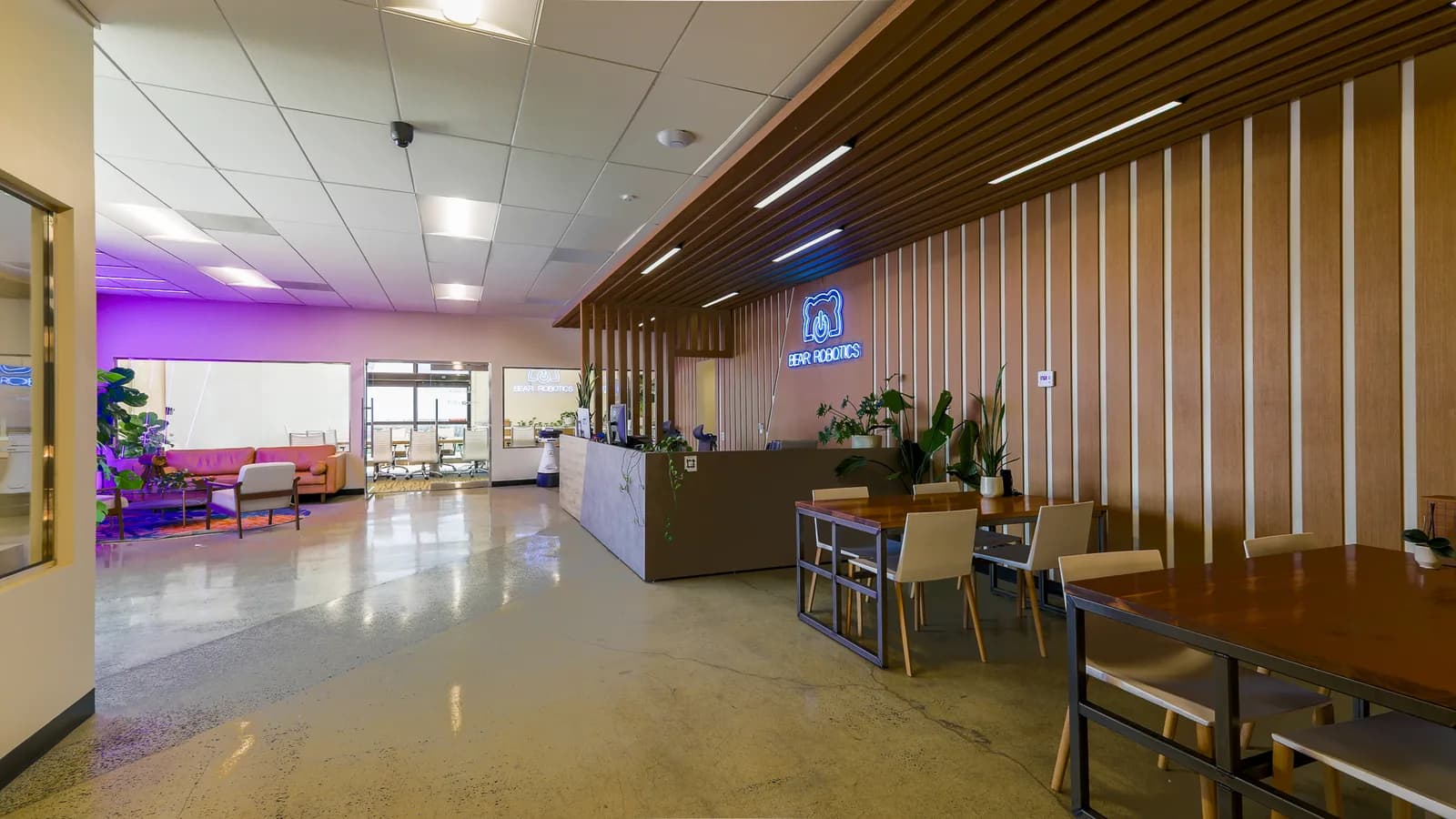Bear Robotics logo in blue neon on a wooden slat wall behind the reception desk