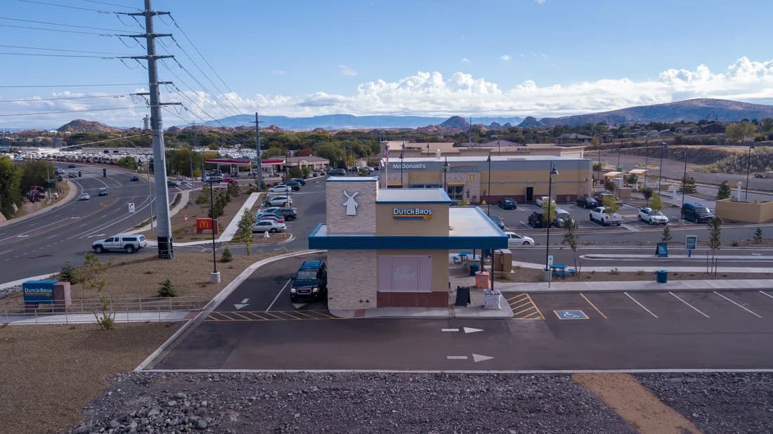 Aerial view of a Dutch Bros drive-thru coffee shop with nearby McDonald's and parking lots