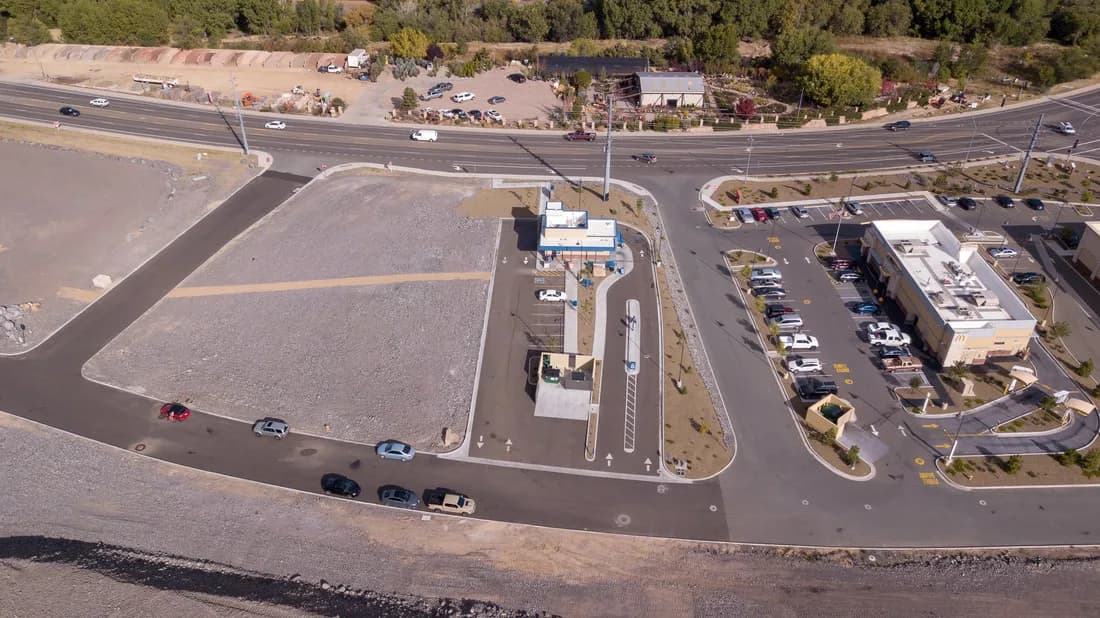 Aerial view of a commercial lot with a drive-through restaurant, parking areas and queued cars