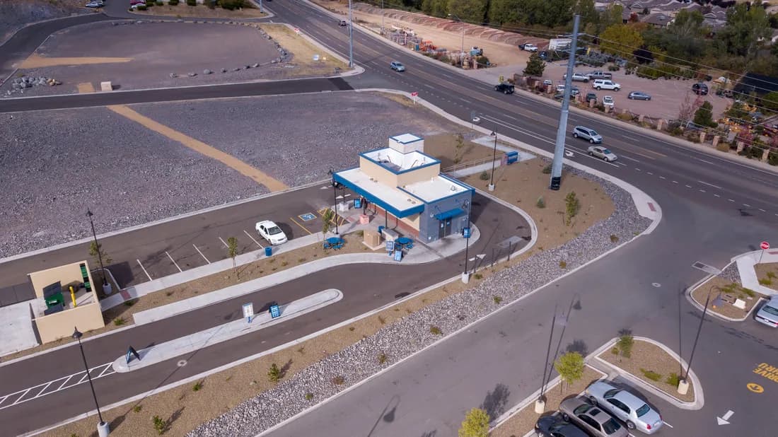 Small blue-and-beige drive-through building seen from above, with parking lot and surrounding roads