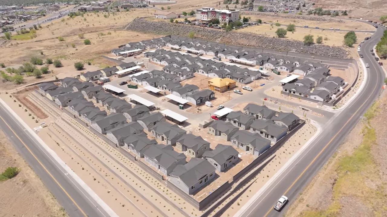 Aerial view of a new housing development with rows of single-story homes and surrounding roads