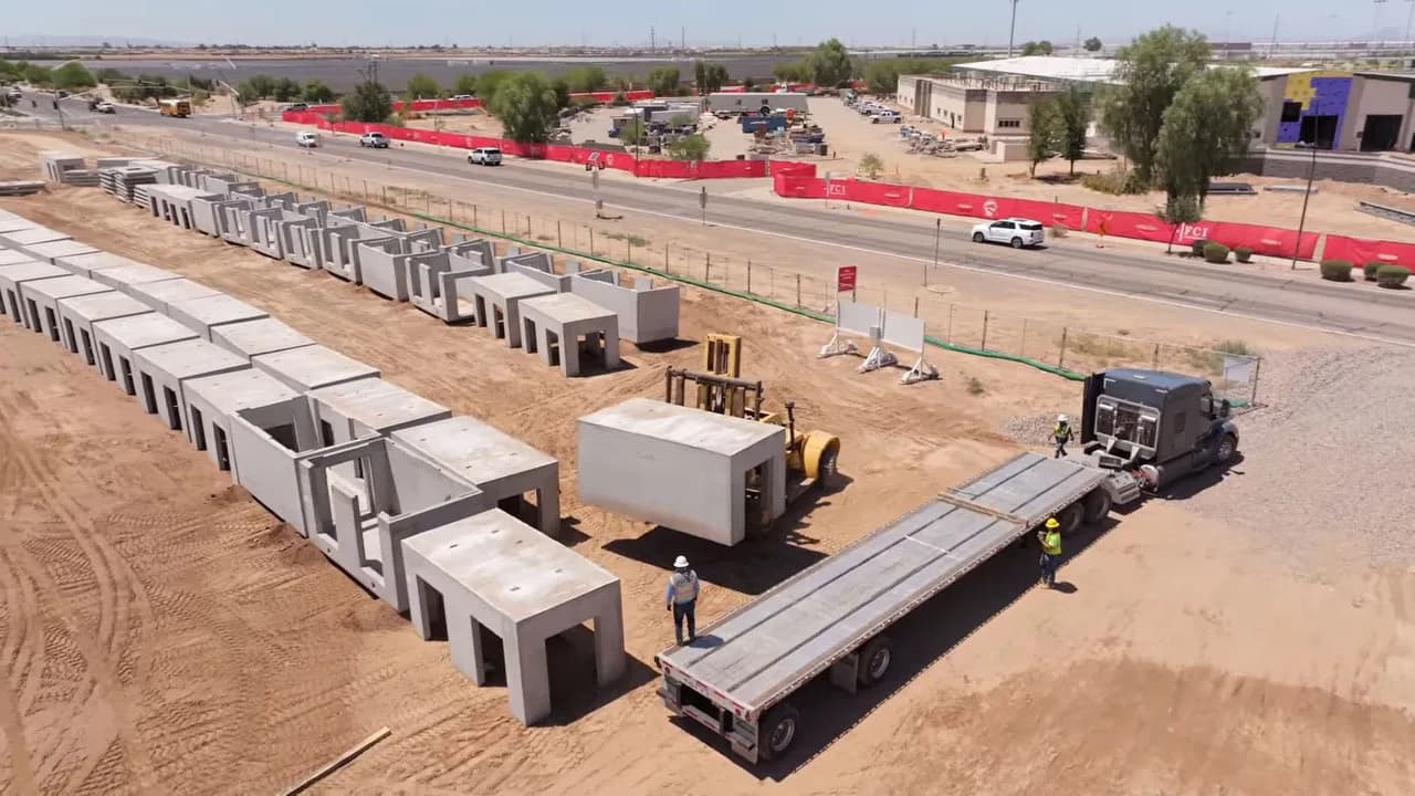Aerial view of a construction site with rows of precast concrete boxes, flatbed truck and workers