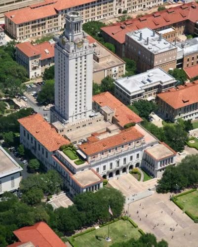 Aerial view of a campus with a tall clock tower surrounded by red-tiled buildings and courtyards