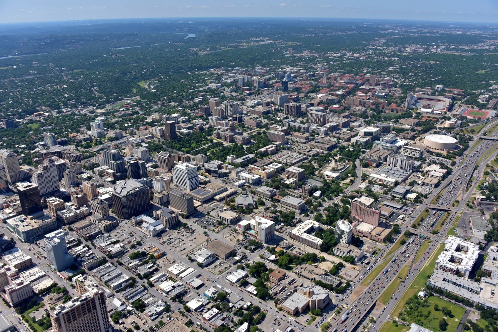 Aerial view of a downtown skyline with tall buildings, a circular stadium, and a highway