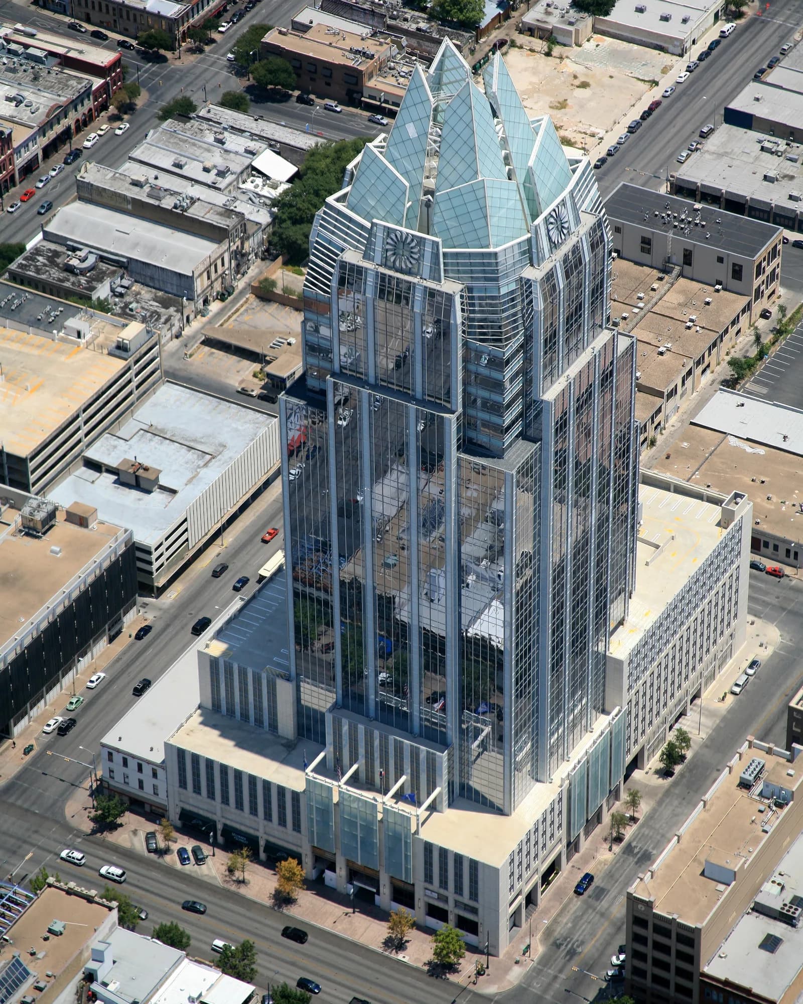 Aerial view of a glass skyscraper with pyramid-like spires rising above the city grid