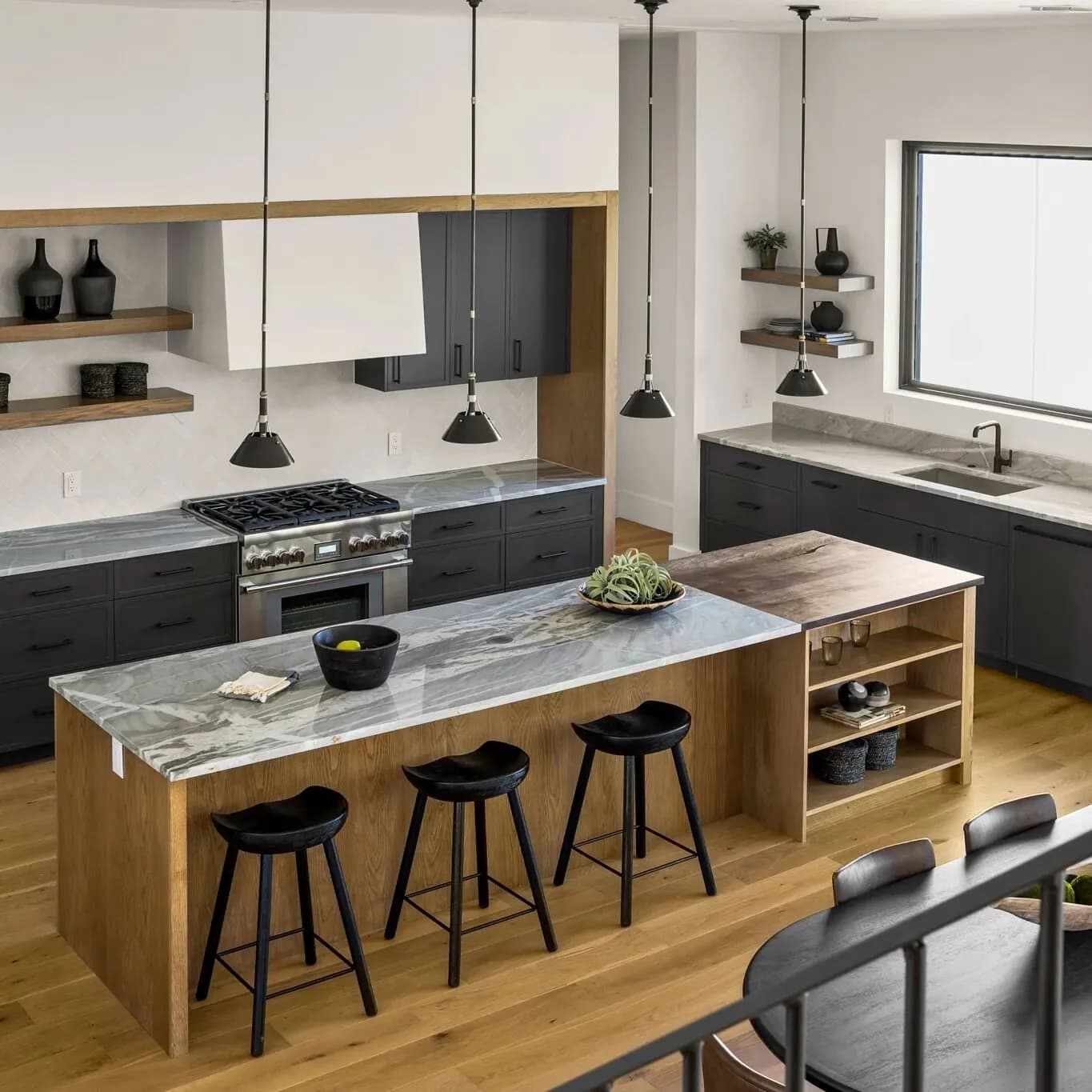Modern kitchen with marble island, dark gray lower cabinets, white upper cabinets, and pendant lights