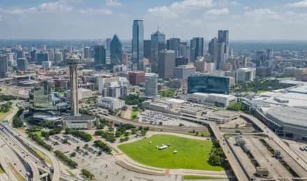 Aerial view of a city skyline with numerous tall buildings and a large green park in the foreground