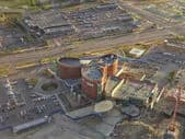 Aerial view of an industrial complex with round towers and surrounding parking areas