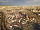 Aerial view of a construction site with partially built structures, dirt roads, and cleared land