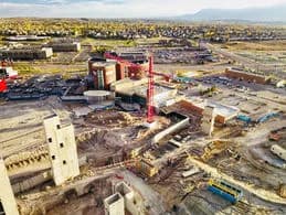 Aerial view of a construction site with a red crane, concrete structures, and earthworks
