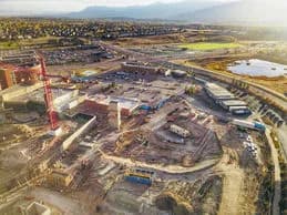 Aerial view of a construction site with a red crane, buildings under construction, dirt roads