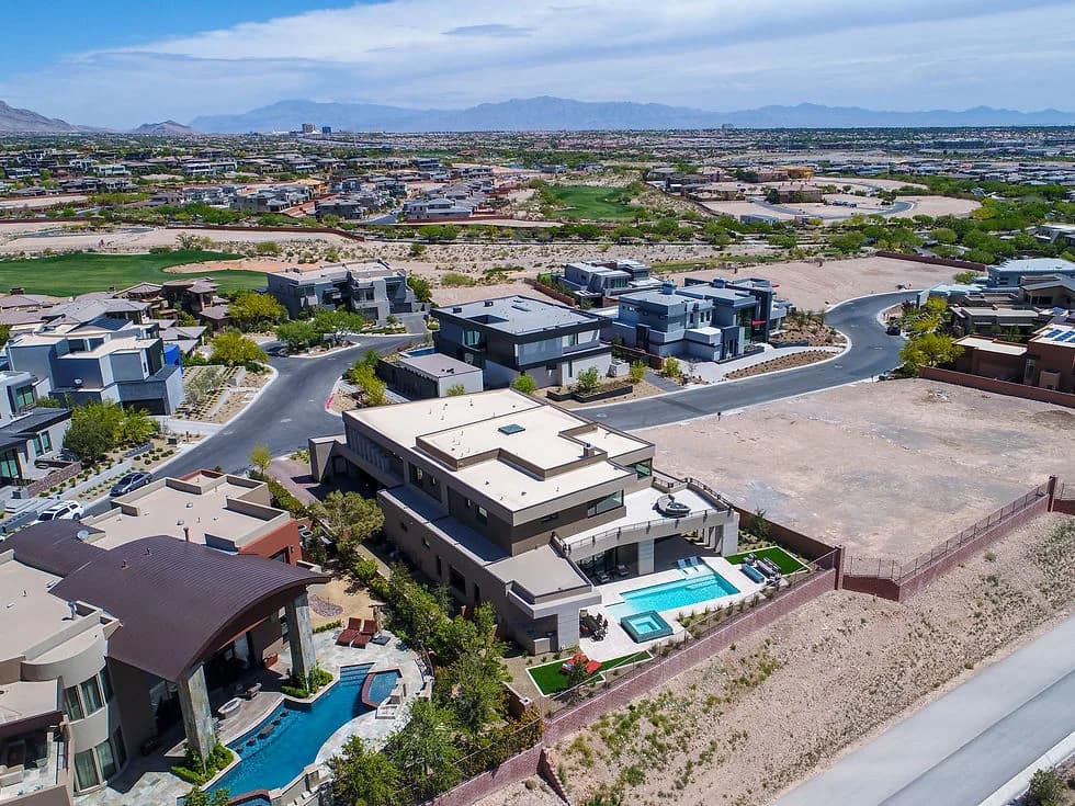 Aerial view of a modern suburban neighborhood with houses, pools, and desert landscaping