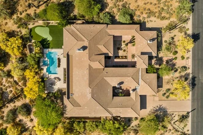Top-down view of a large desert home with courtyard, swimming pool, and surrounding trees