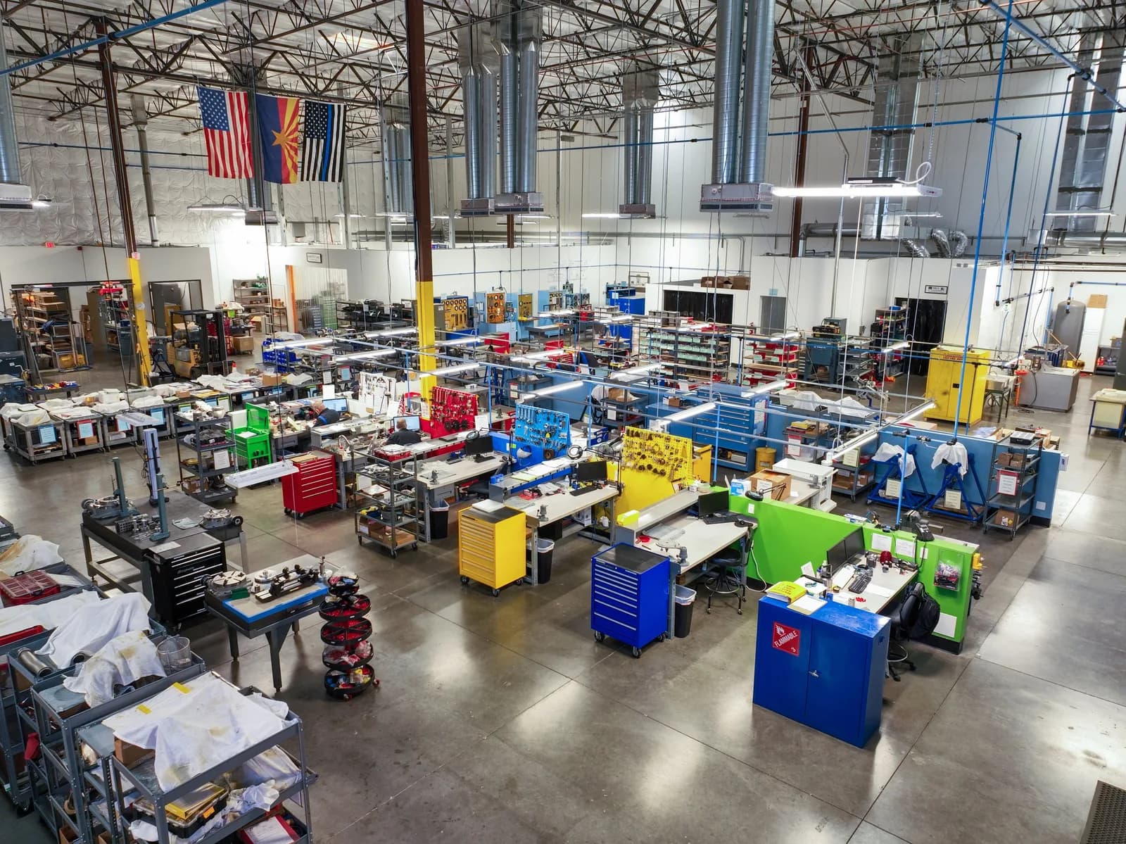 High-angle view of a large workshop with rows of workbenches and colorful tool cabinets