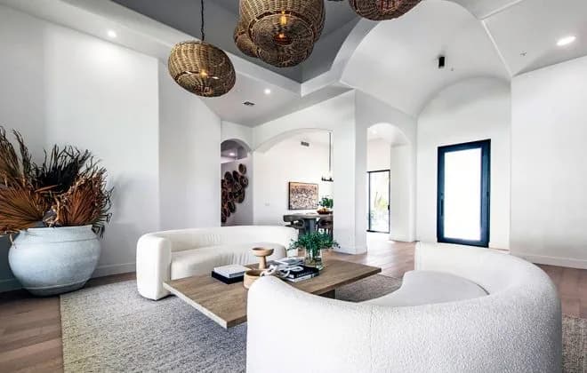 Bright modern living room with curved white sofas, low wooden coffee table, woven pendant lights