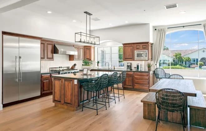 Bright kitchen with wooden cabinets, large island with bar stools and dining nook by a window