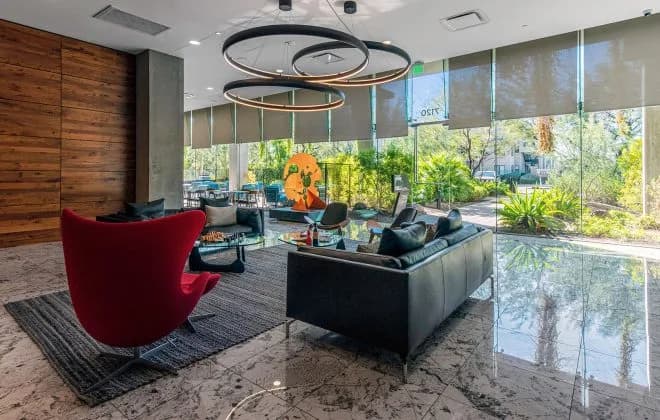Modern lobby with red egg chair, leather sofas, circular pendant lights and floor-to-ceiling windows