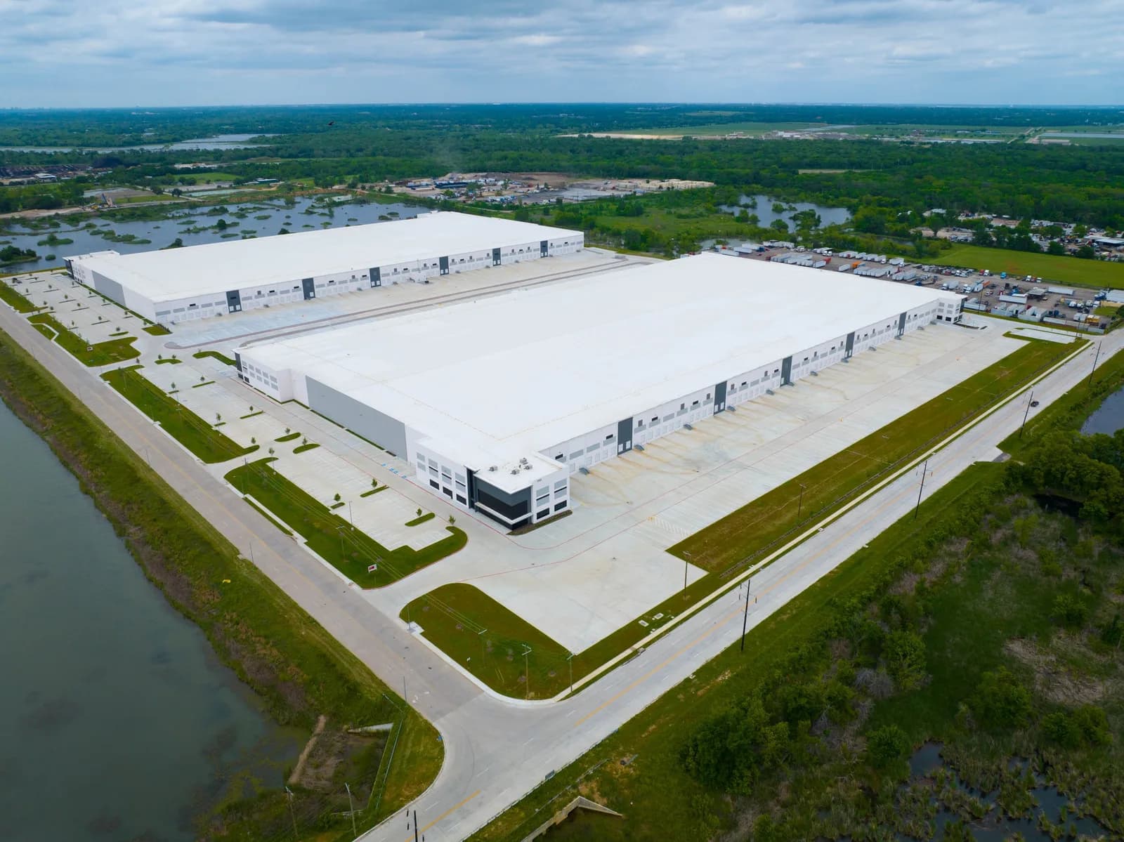 Aerial view of a large white industrial warehouse complex with multiple loading bays and a parking lot