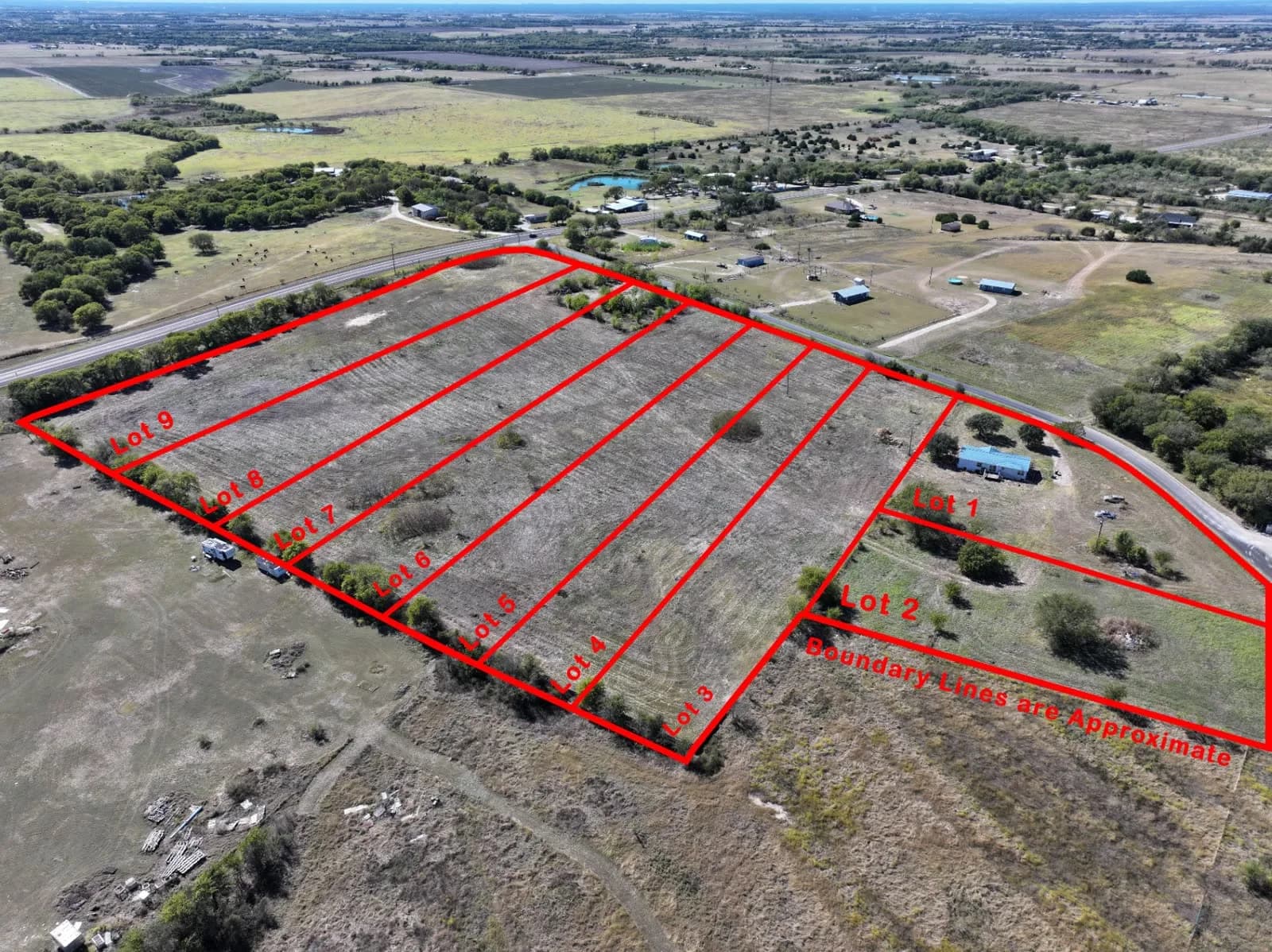 Aerial drone view of nine red outlined lots labeled Lot 1 to Lot 9 with boundary lines approximate