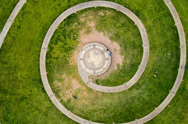 Aerial view of a spiral concrete path circling a grassy area with a central platform and people