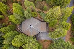 Aerial view of a multi-roof building surrounded by dense green trees