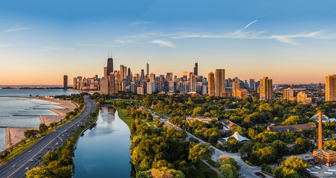 Urban city skyline at sunset with a river, beach, and park in the foreground