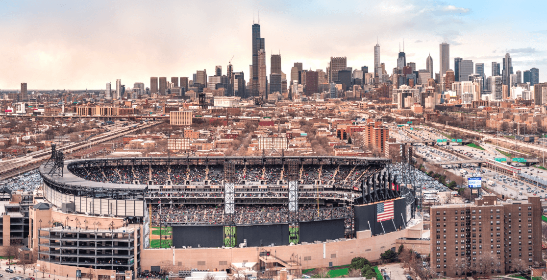 Baseball stadium filled with spectators, with a distant city skyline of tall buildings