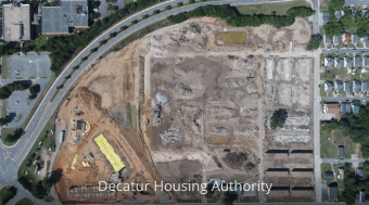 Aerial view of a construction site with cleared lots and foundation outlines by a curved road