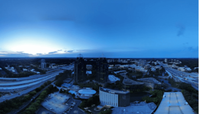Aerial cityscape at blue hour with tall buildings, roads and green spaces