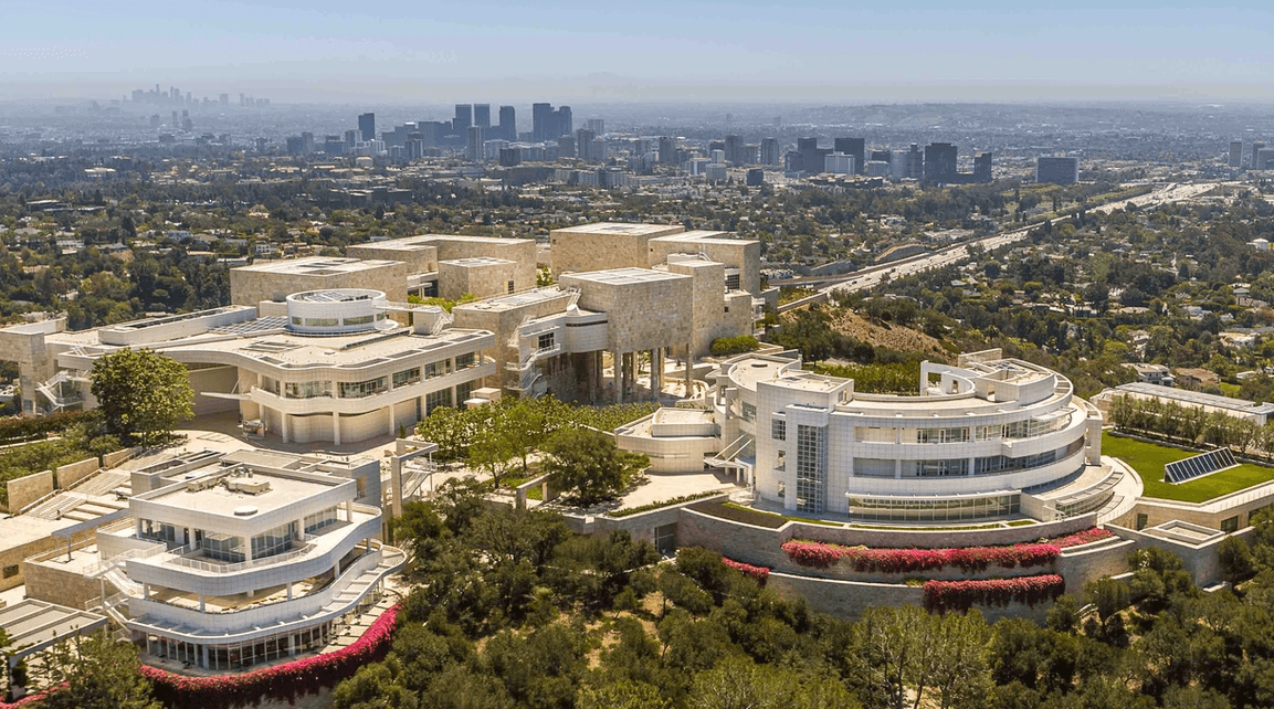 Drone shot of a modern white architectural complex with curved glass facades and landscaping
