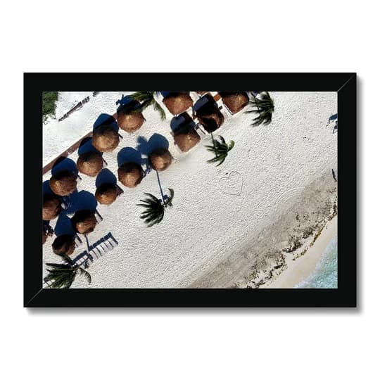 Aerial view of a beach with rows of thatched umbrellas, palm trees and white sand along the shoreline
