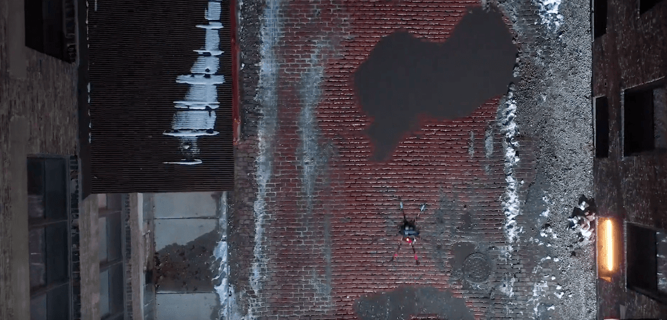 Aerial view of a drone hovering over a brick courtyard between two buildings with snow patches