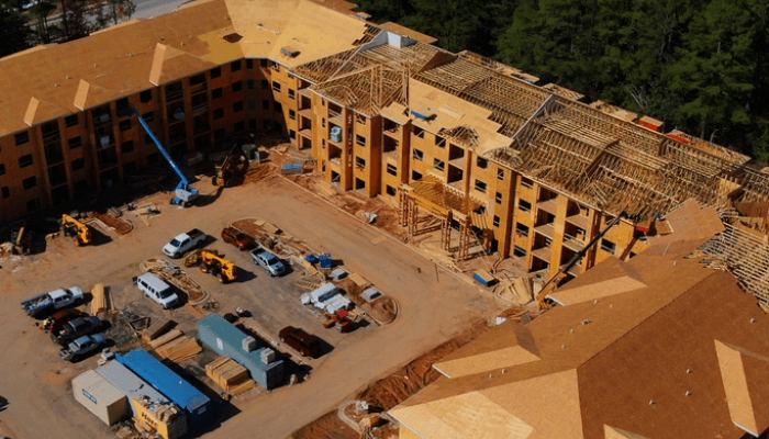 Bird's-eye view of a large construction site with a u-shaped building, scaffolding, and construction vehicles