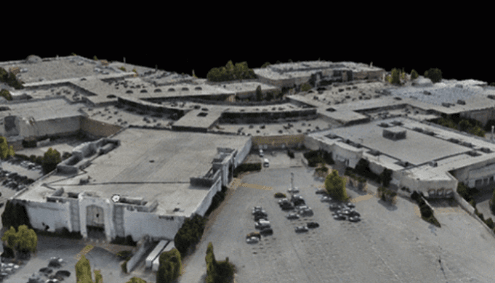 Aerial view of a large building complex with a parking lot and cars