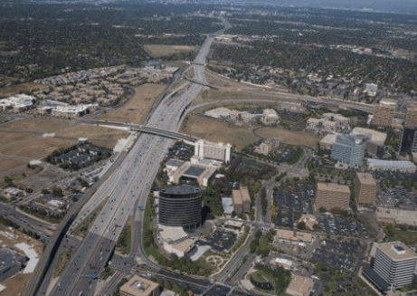 Aerial view of a city with a large highway interchange and surrounding buildings