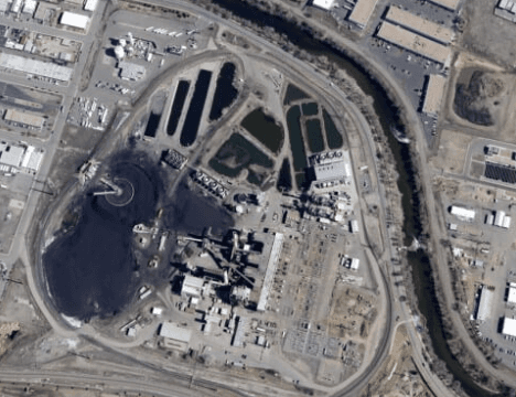 Aerial view of an industrial complex with buildings, roads, a curved river and ponds
