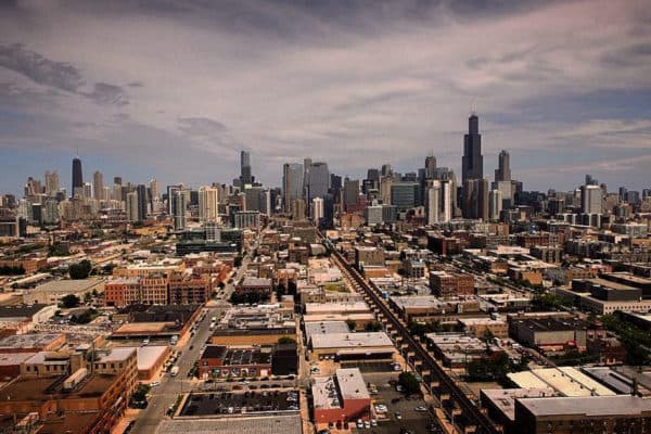 Aerial view of a city with a dense downtown, grid streets, and a distant skyline of tall buildings
