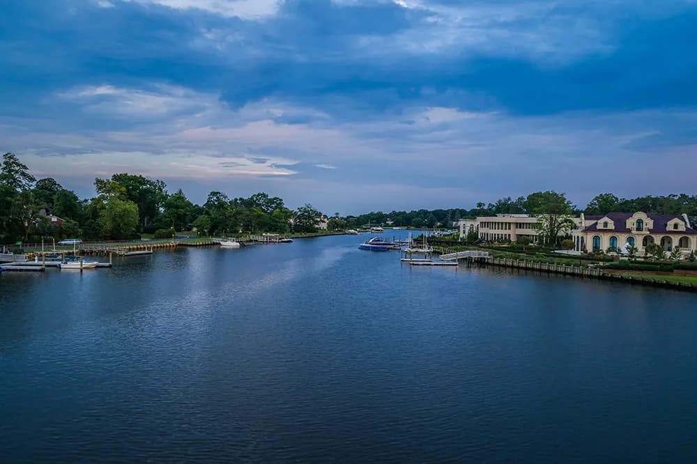 Waterway with docks and boats along a waterfront with trees and buildings on both sides