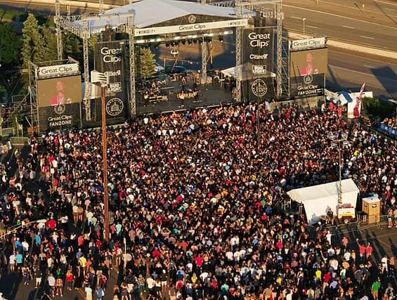 Aerial view of an outdoor concert stage with a large crowd and Great Clips banners