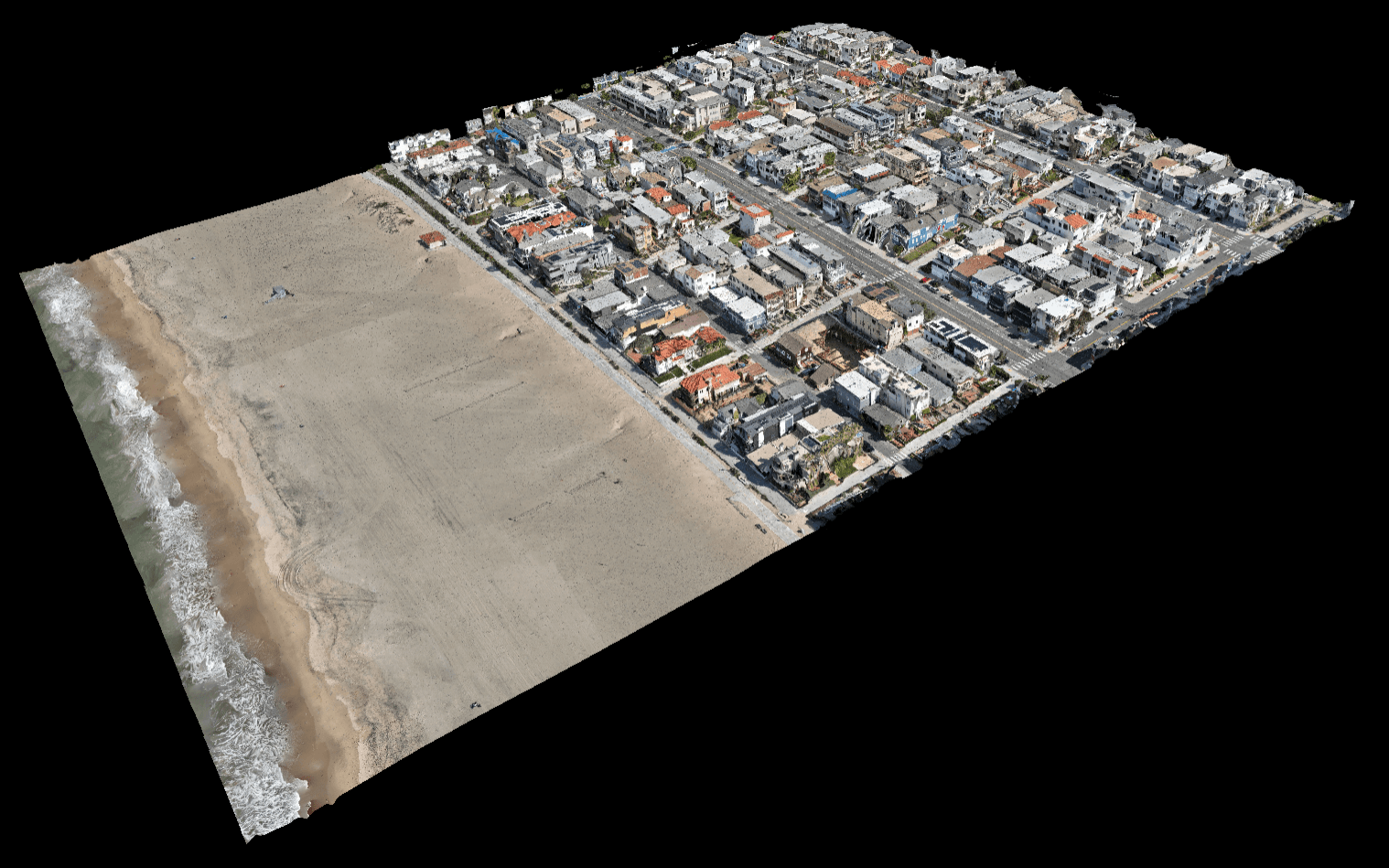 Aerial view of a coastal town with a sandy beach on the left and a grid of houses on the right