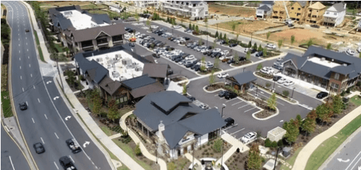 Aerial view of a campus-like complex with multiple buildings, a parking lot, and roads